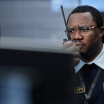 Middle Aged Black Man Monitoring Security Systems While Using Walkie Talkie